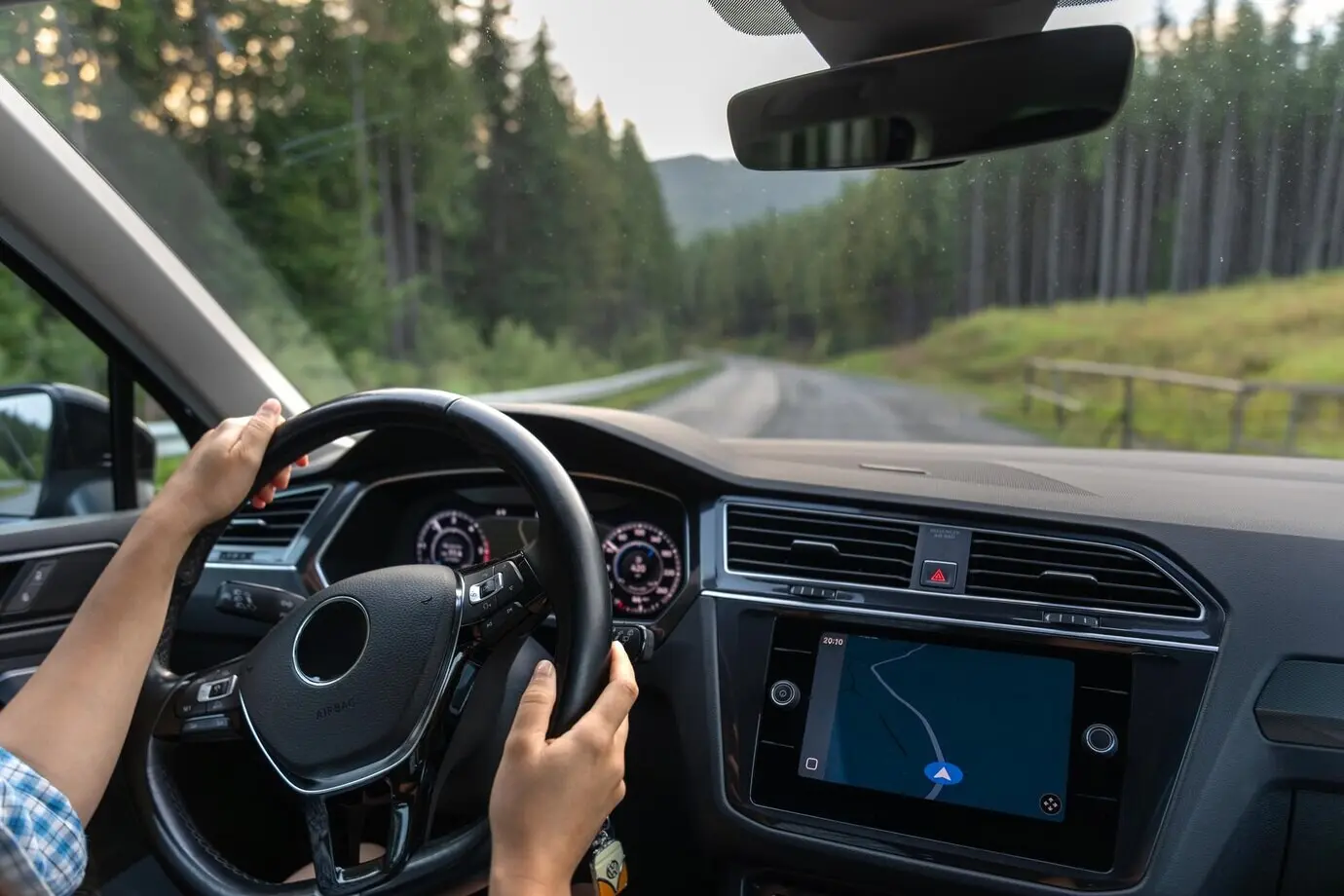 Вид из салона автомобиля на лесную дорогу во время движения на современном автомобиле.