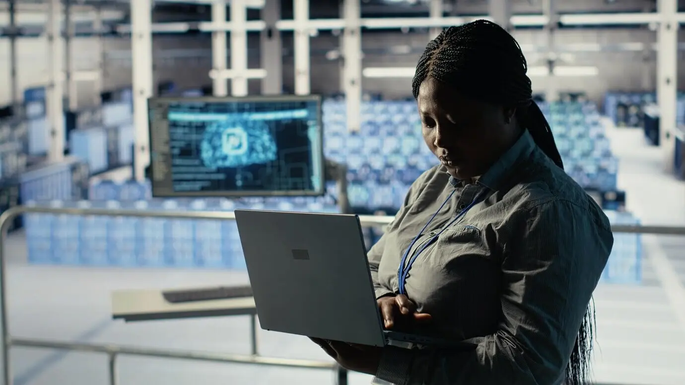 Администратор центра обработки данных проверяет информационную панель ИИ с помощью ноутбука в ходе проверки систем установок.