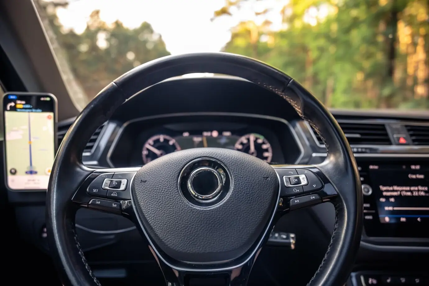 Крупный план рулевого колеса в современном салоне автомобиля с технологическим оснащением для вождения.